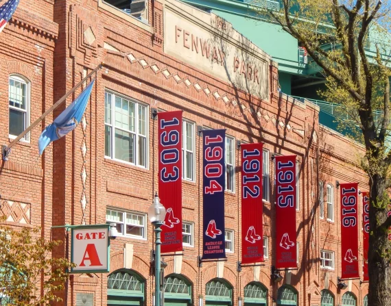Vertical pole banners mounted on banner arms along a brick stadium facade.